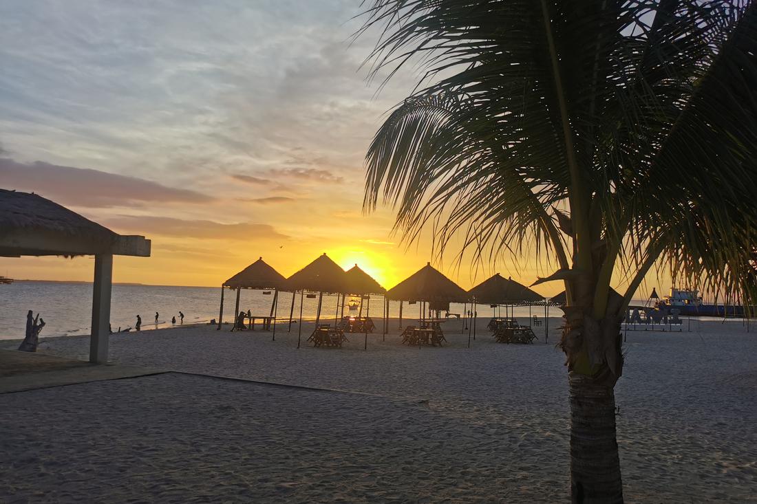 Beach at sunset with nipa huts, Philippines